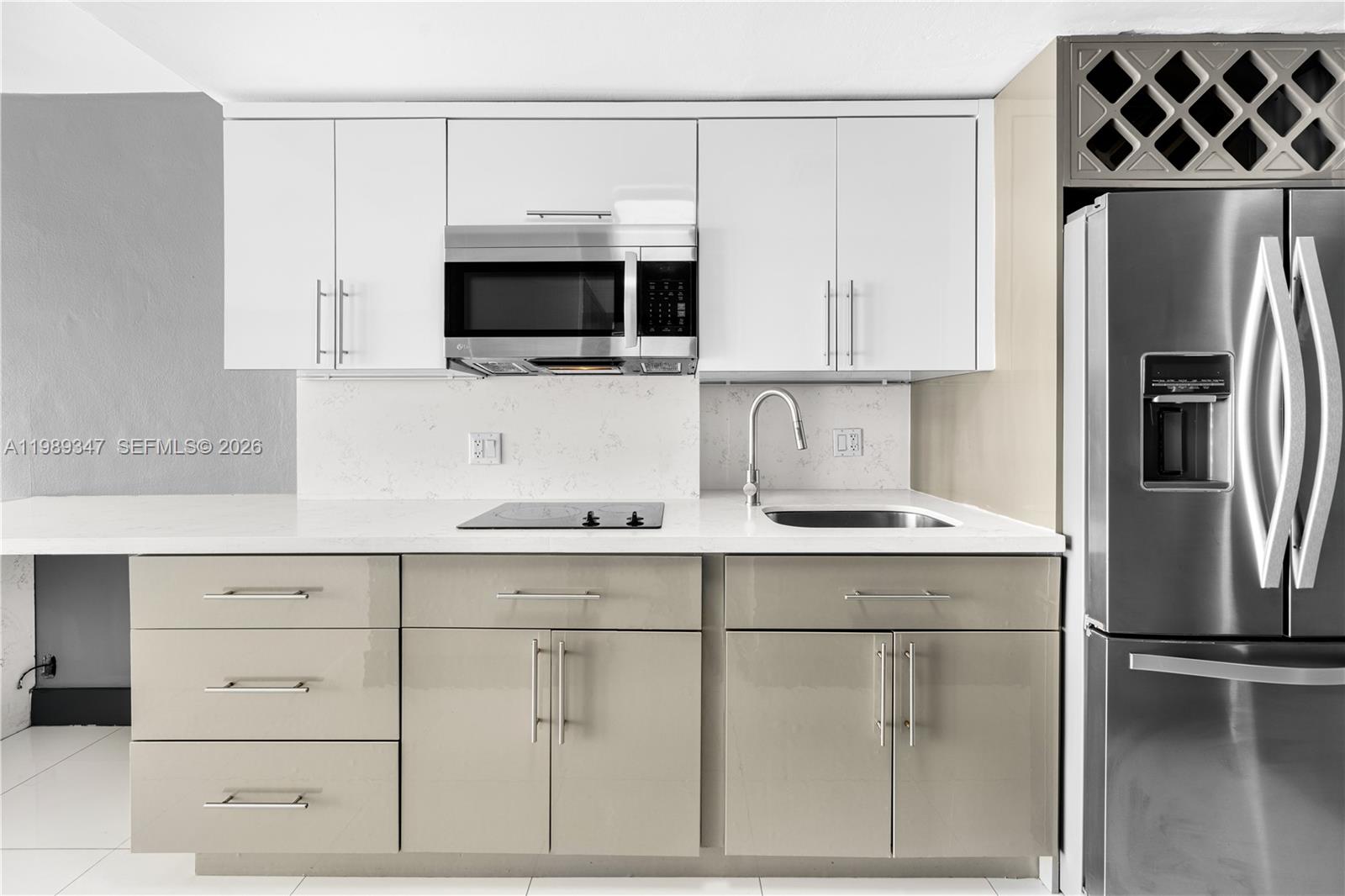 A modern kitchen features white upper cabinets, taupe lower cabinets, and stainless steel appliances — 3301 NE 5th AVE # 1212, Miami FL 33137, MIAMI, FL