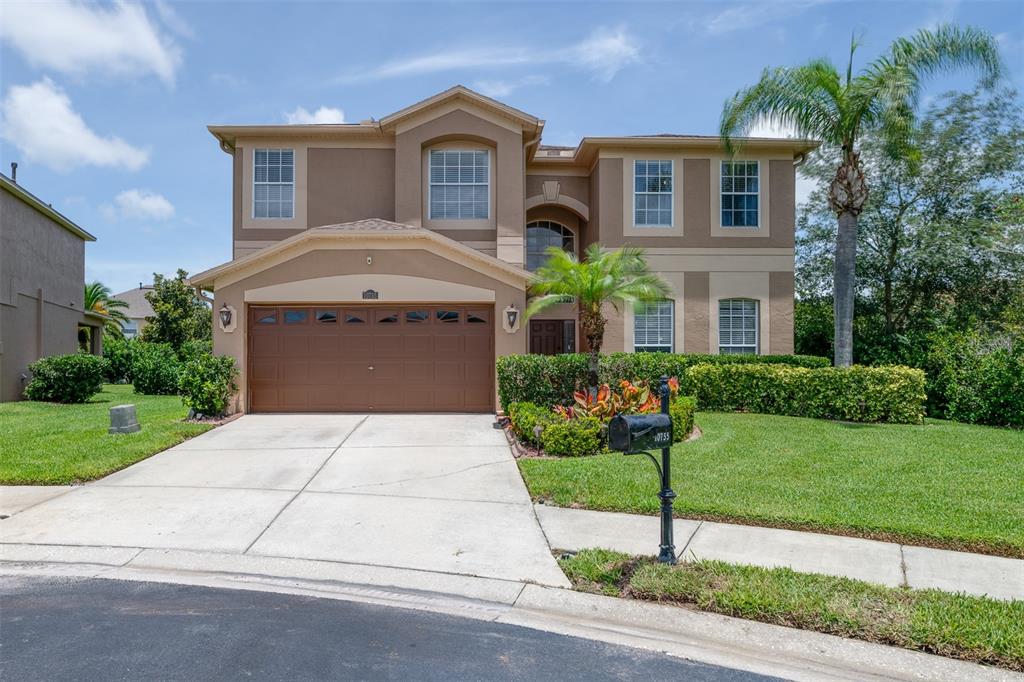 A two-story suburban house with a brown garage, beige stucco exterior, and a front lawn — 10755 NORTHRIDGE COURT, TRINITY, FL