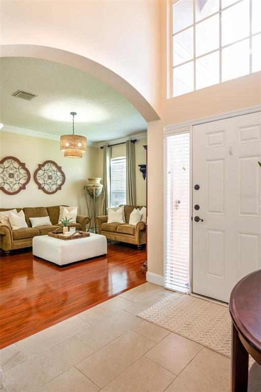 An entryway with tile flooring leads into a living room featuring hardwood floors and furniture — 10755 NORTHRIDGE COURT, TRINITY, FL