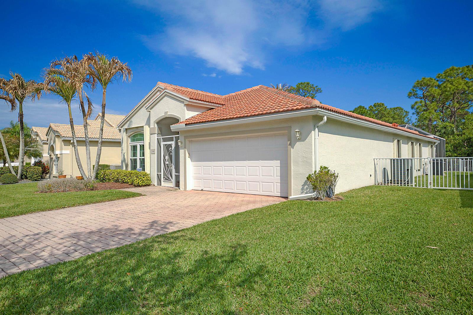 A single-story house with a tiled roof, white garage door, and a brick paver driveway — 7004 SE Twin Oaks Circle, Stuart FL 34997, STUART, FL
