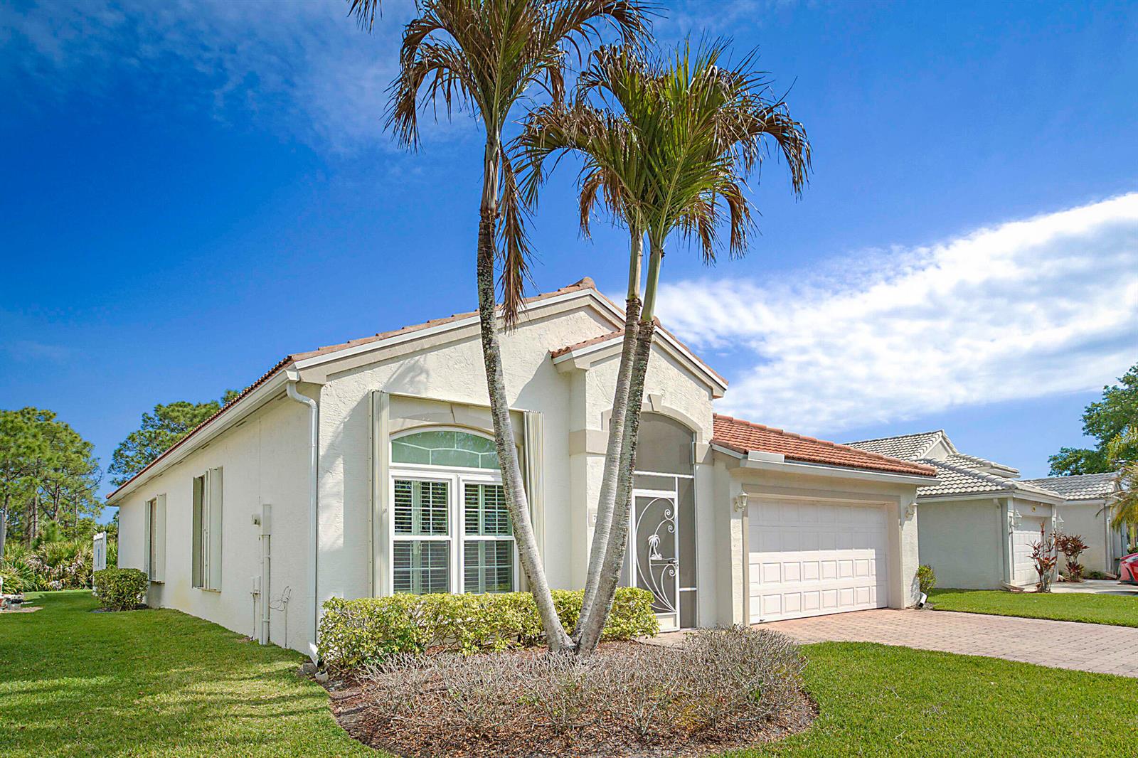 A single-story stucco house with a tile roof, two palm trees, and a paved driveway — 7004 SE Twin Oaks Circle, Stuart FL 34997, STUART, FL