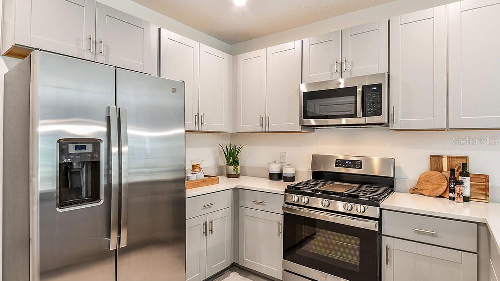 A kitchen features light gray cabinets, stainless steel appliances, and white countertops — 12219 TEMPEST LANE, HUDSON, FL