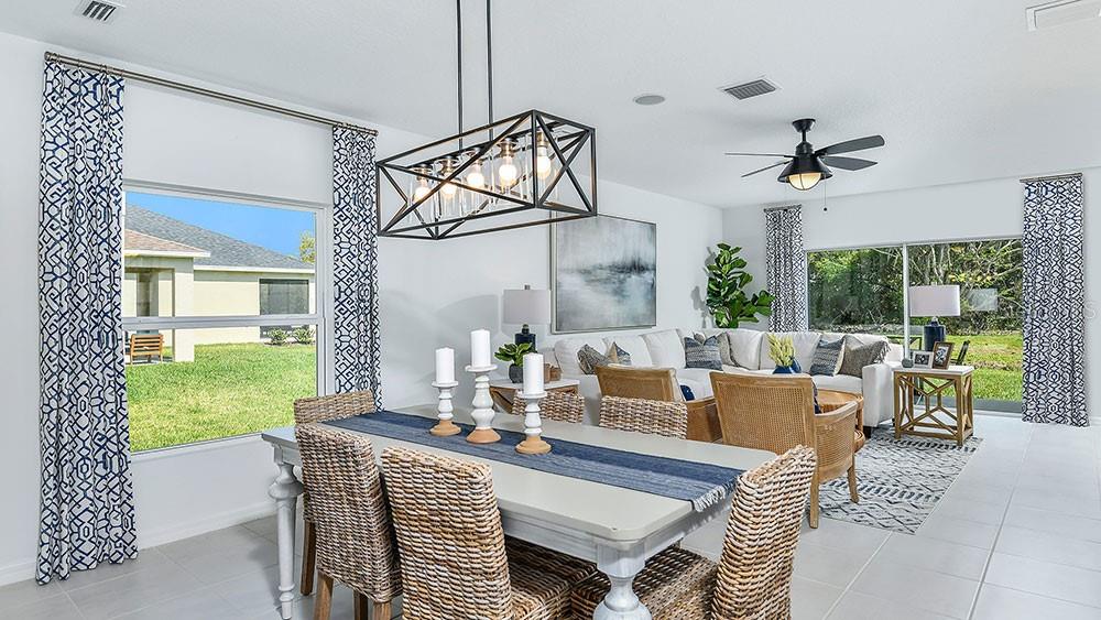 A dining area with a rectangular table and wicker chairs sits before a living room — 12219 TEMPEST LANE, HUDSON, FL