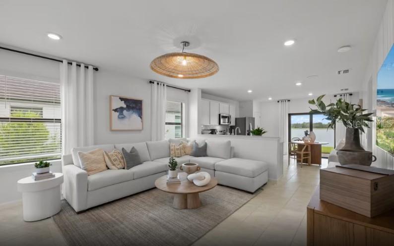 A living room with a sectional sofa, round coffee table, and open kitchen in background — 810 BALLEBY TRAIL, BRADENTON, FL