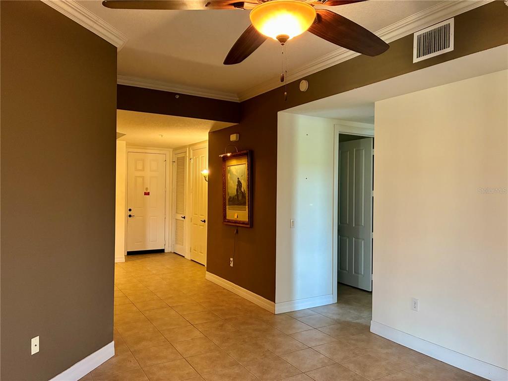A tiled hallway leads to a white door, featuring brown walls and a ceiling fan — 98 VIVANTE BOULEVARD UNIT 98412, PUNTA GORDA, FL