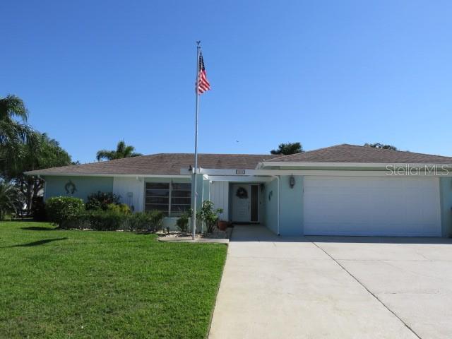 A single-story house with a light blue exterior, a two-car garage, and an American flag — 7207 15TH AVENUE DRIVE W, BRADENTON, FL