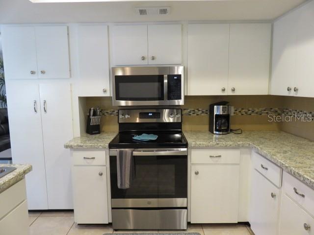 A kitchen features white cabinets, stainless steel appliances, and speckled granite countertops — 7207 15TH AVENUE DRIVE W, BRADENTON, FL