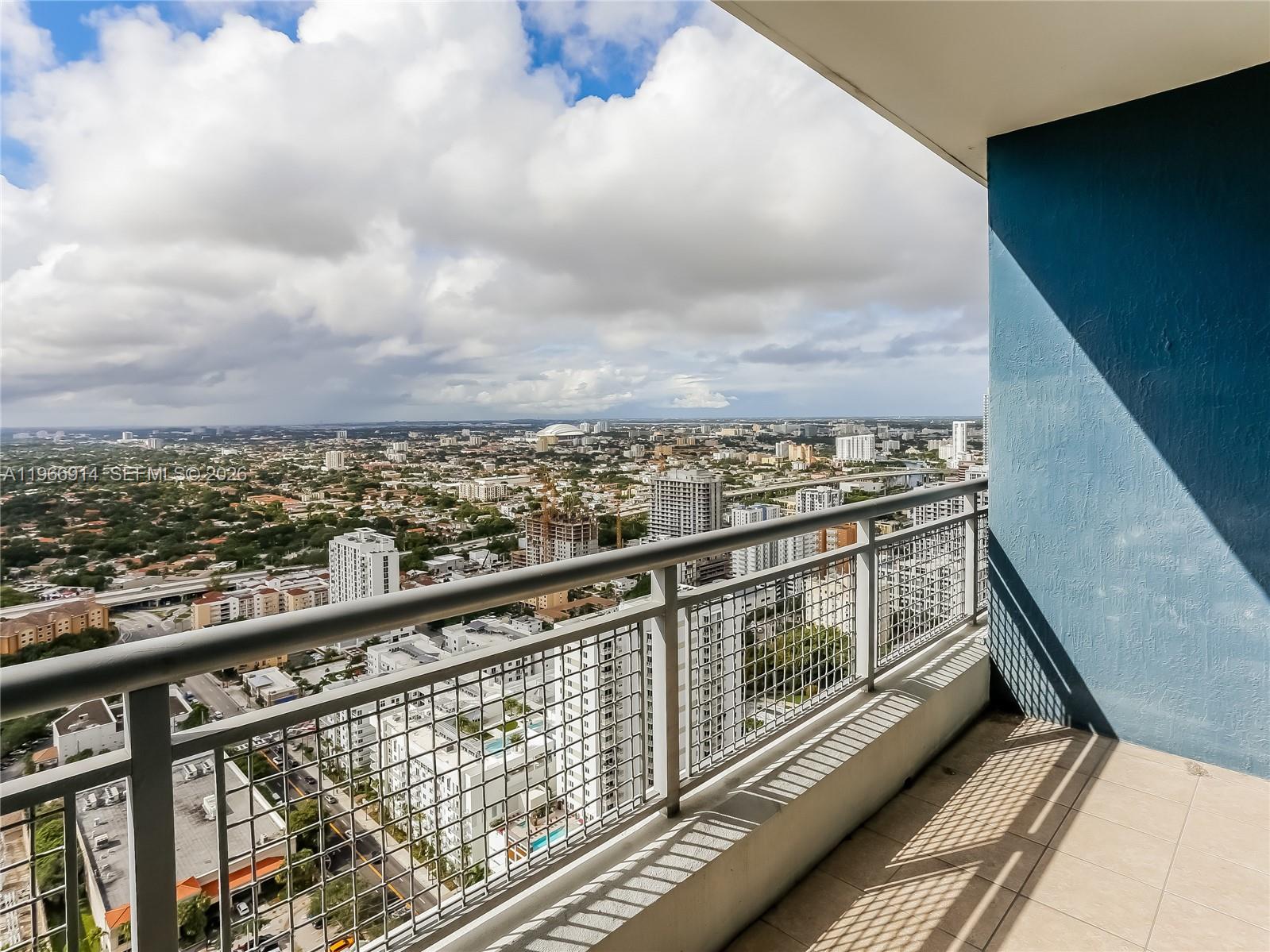 A high-rise balcony with a metal railing overlooks a sprawling city under a cloudy sky — 60 SW 13th St # 3404, Miami FL 33130, MIAMI, FL