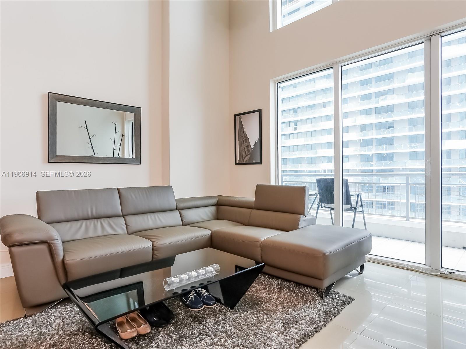 A living room features a gray sectional sofa, a glass coffee table, and floor-to-ceiling windows — 60 SW 13th St # 3404, Miami FL 33130, MIAMI, FL