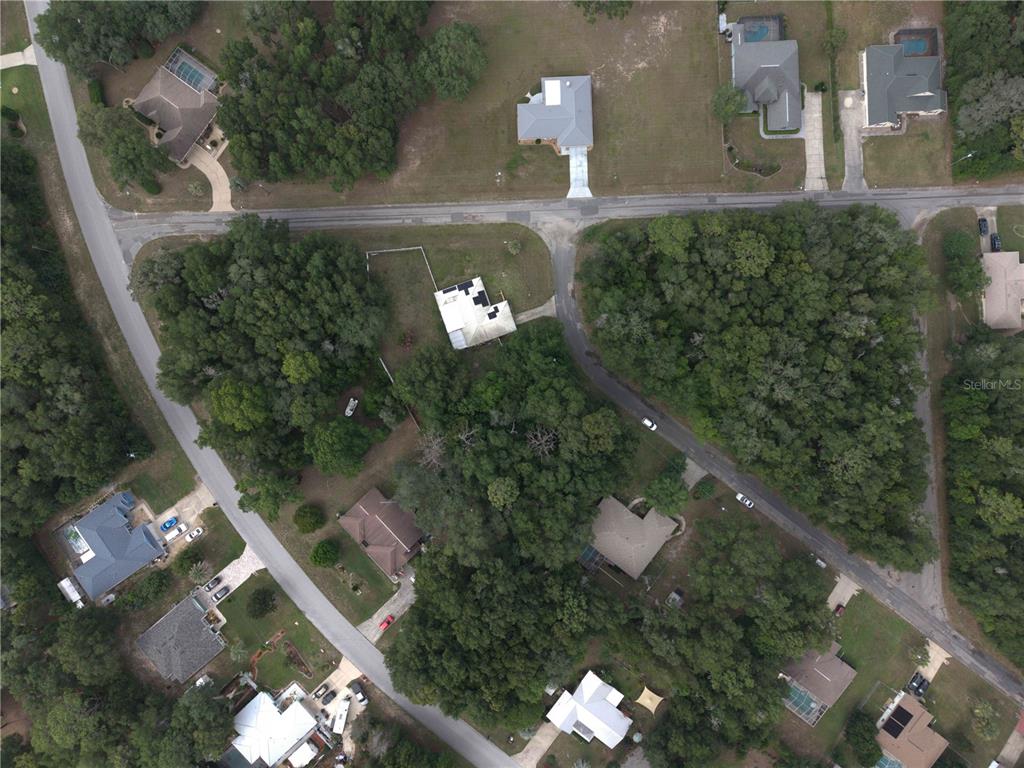 An aerial view shows several houses surrounded by dense trees and paved roads — 8371 N TITLEIST DRIVE, CITRUS SPRINGS, FL