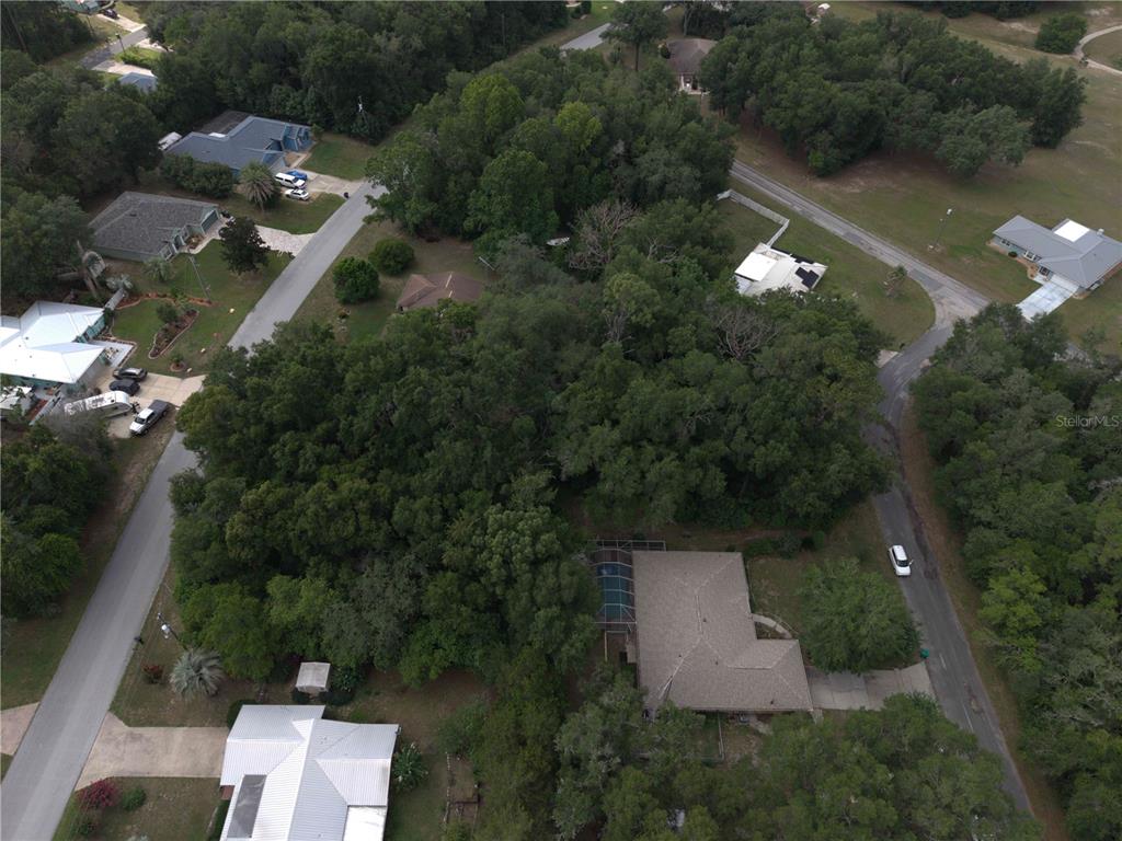 An aerial view shows a residential property with a house surrounded by dense trees — 8371 N TITLEIST DRIVE, CITRUS SPRINGS, FL