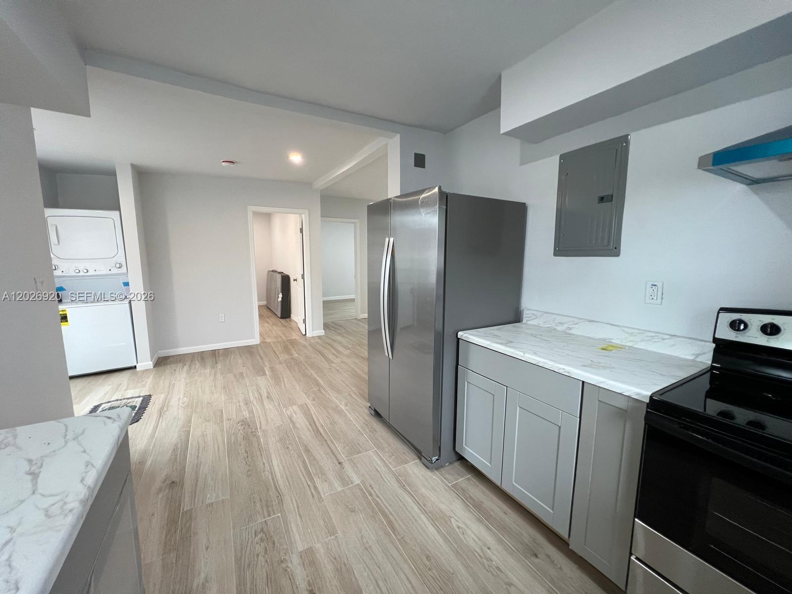 A kitchen features gray cabinets, marble-look countertops, stainless steel appliances, and wood-look tile flooring — MIAMI, FL