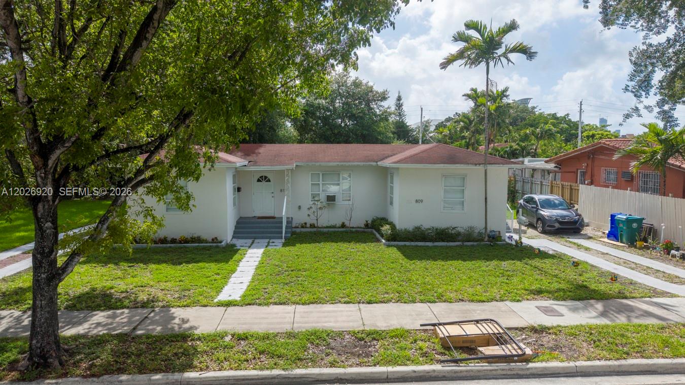 A single-story white house with a red roof sits behind a front lawn and driveway — MIAMI, FL