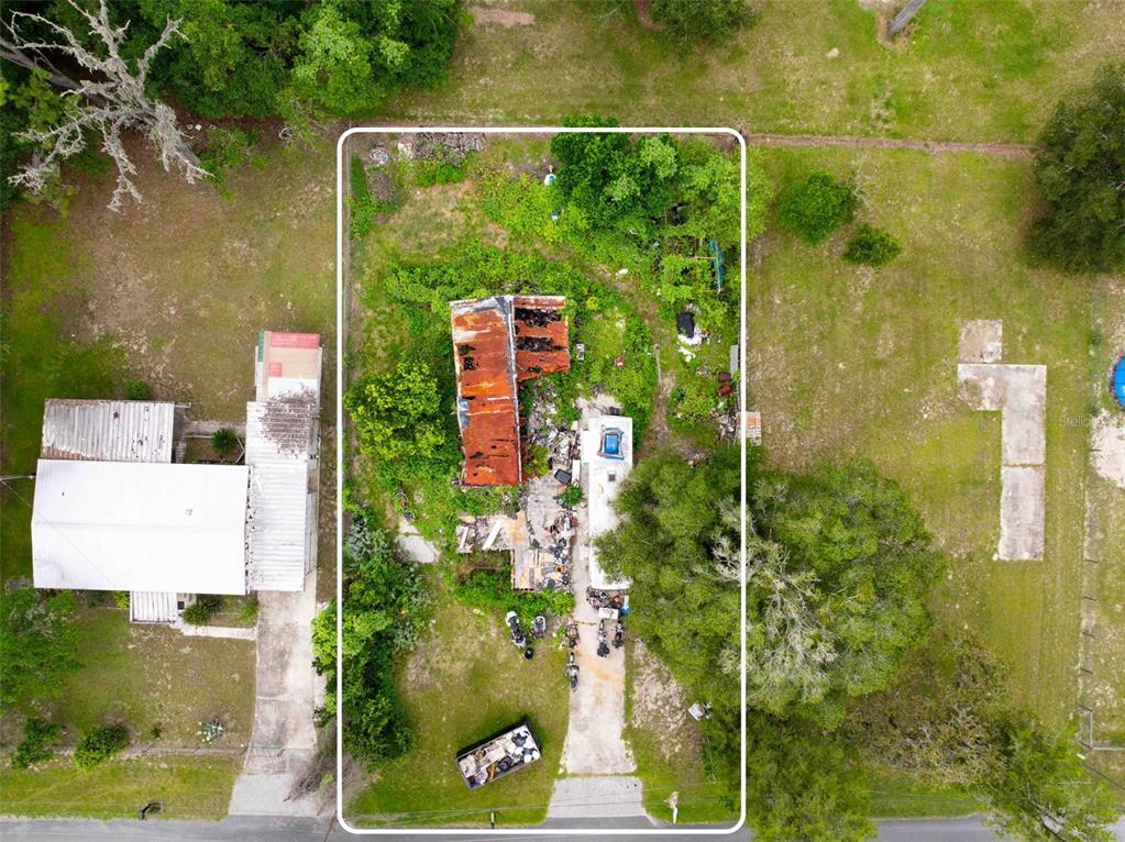 An aerial view shows a dilapidated structure with a rusted roof on a grassy lot — 7080 N PEARL POINT, HERNANDO, FL
