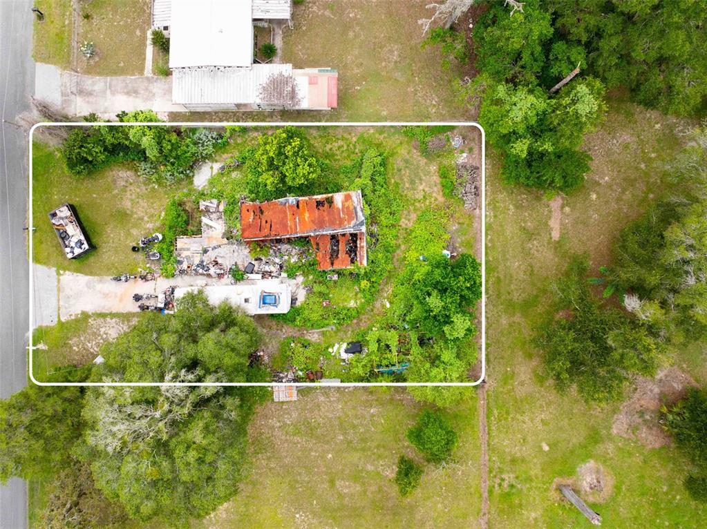 An aerial view shows a dilapidated mobile home with a rusted roof on a wooded lot — 7080 N PEARL POINT, HERNANDO, FL