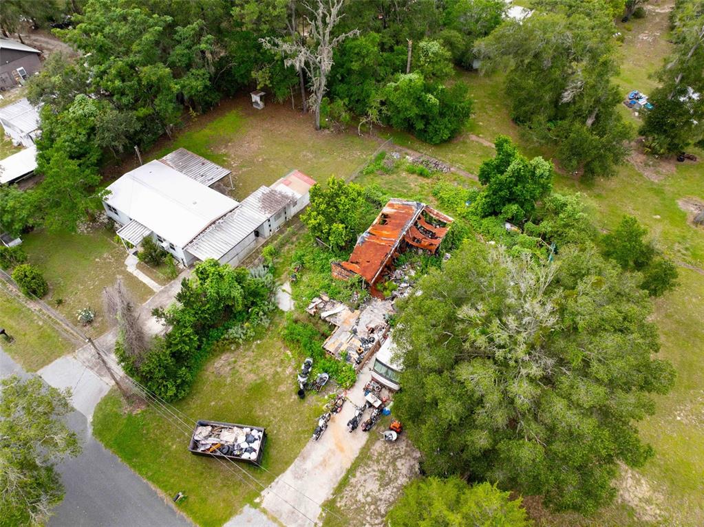 An aerial view shows a property with a house, a fire-damaged structure, and a dumpster — 7080 N PEARL POINT, HERNANDO, FL