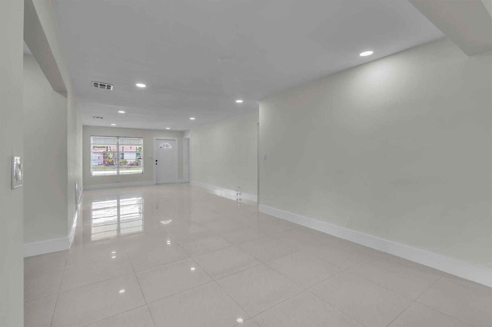 An empty room features white walls, recessed lighting, and glossy light-colored tile flooring — 3262 Pierce Street, Hollywood FL 33021, HOLLYWOOD, FL