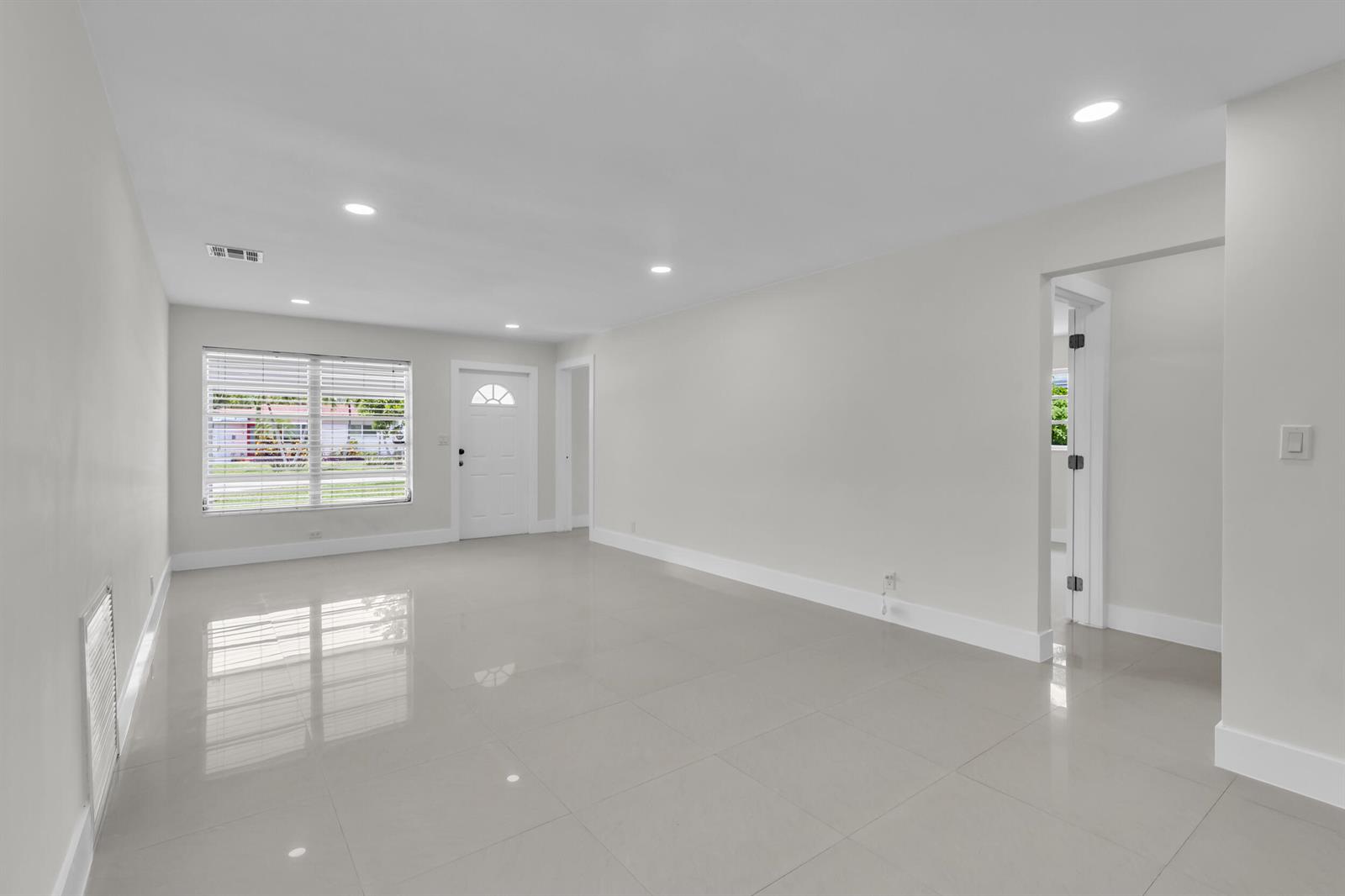 A bright, empty living room features light gray tile flooring, white walls, and recessed lighting — 3262 Pierce Street, Hollywood FL 33021, HOLLYWOOD, FL