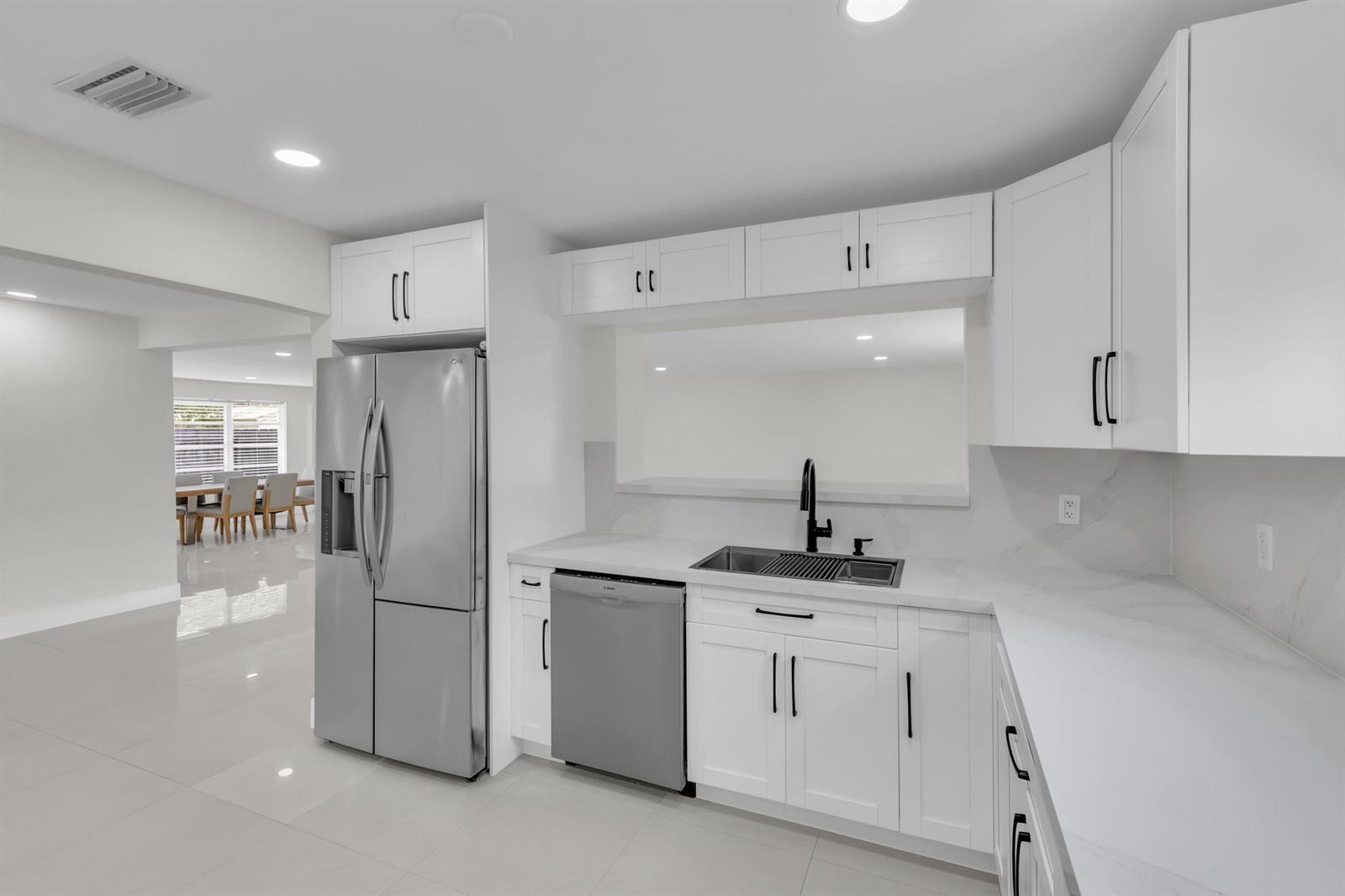 A modern kitchen features white cabinets, stainless steel appliances, and a marble-look countertop — 3262 Pierce Street, Hollywood FL 33021, HOLLYWOOD, FL