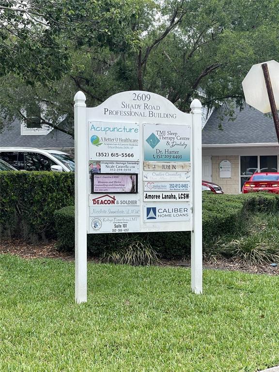 A white sign lists multiple professional businesses in front of a building with green landscaping — 2609 SW 33RD STREET UNIT 102-3, OCALA, FL