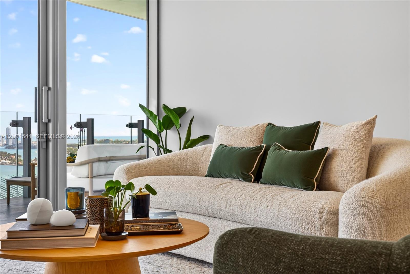 A living room features a cream-colored sofa with green pillows beside a glass balcony door — 700 NE 26 Ter # 3602, Miami FL 33137, MIAMI, FL