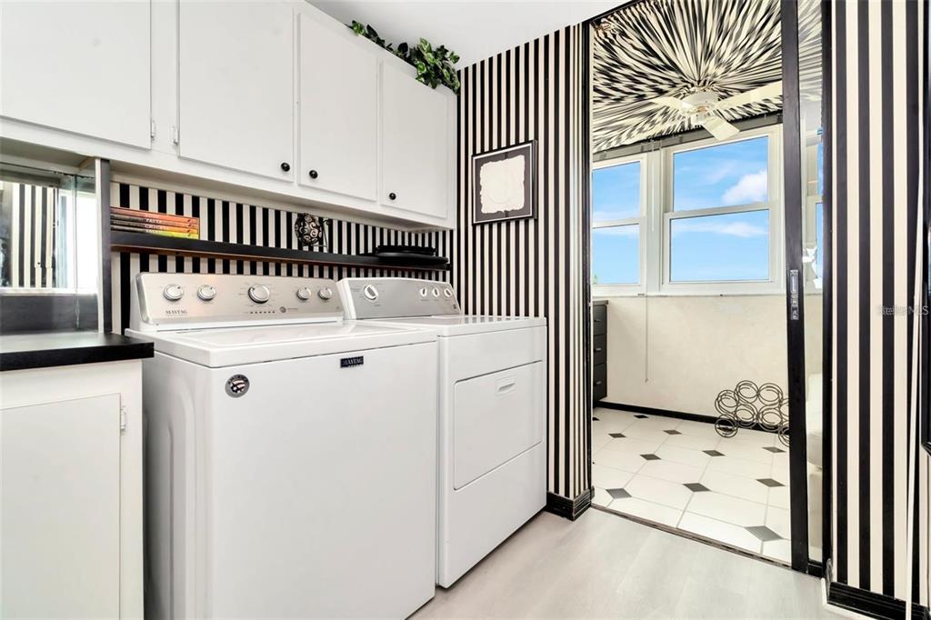 A laundry room with white appliances, black and white striped wallpaper, and an adjacent sunroom — 15462 GULF BOULEVARD UNIT 508, MADEIRA BEACH, FL