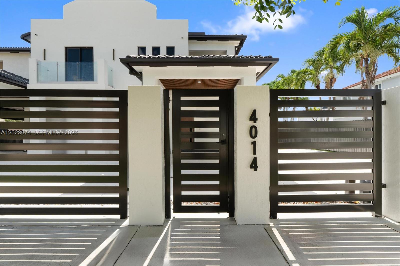 A modern white house features a dark metal gate and fence with the number 4014 — 4014 SW 144th Pl, Miami FL 33175, MIAMI, FL