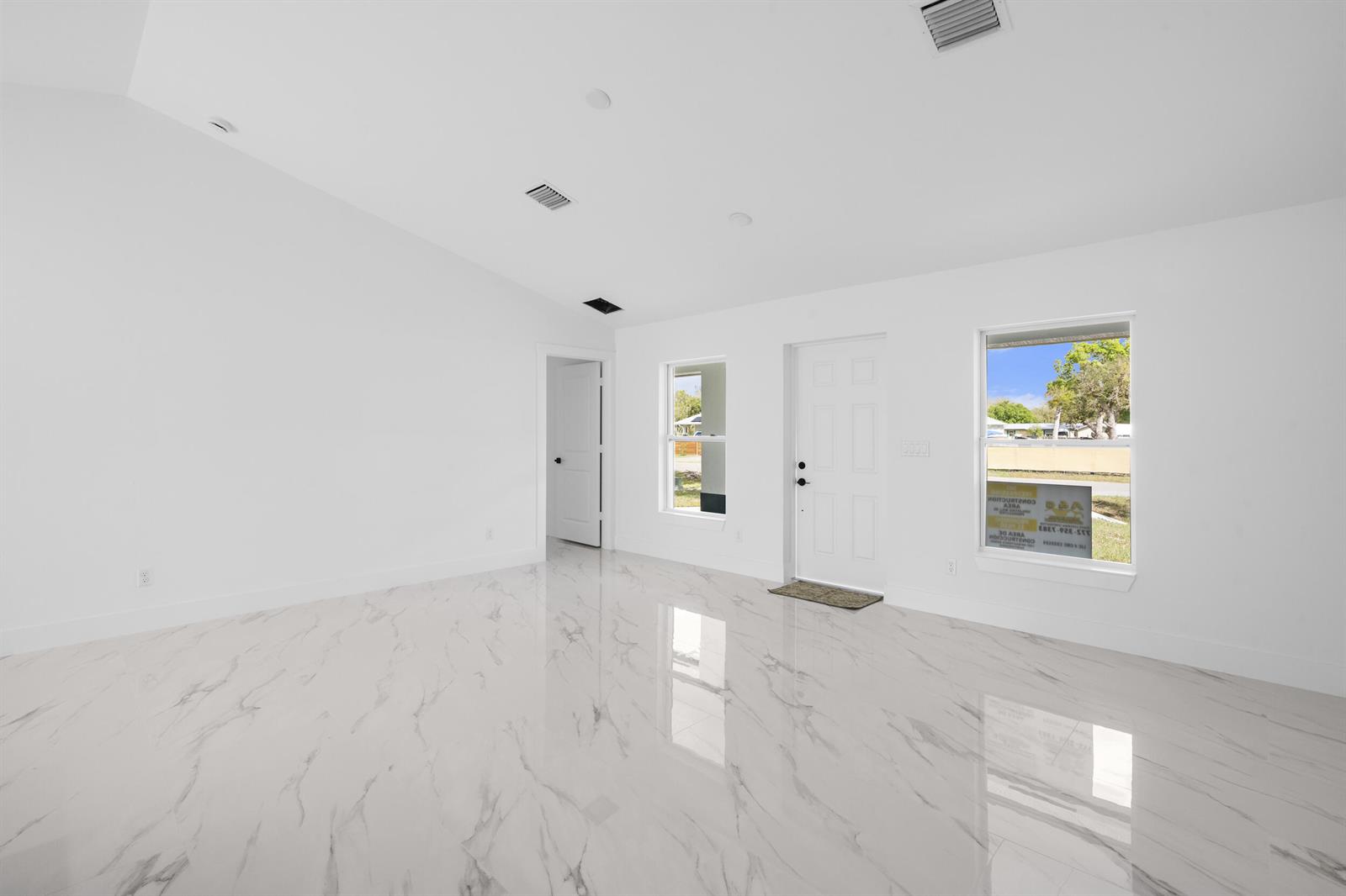 An empty room features white walls, a vaulted ceiling, and polished white marble-patterned tile flooring — 21483 NW 262nd Street, Okeechobee FL 34972, OKEECHOBEE, FL