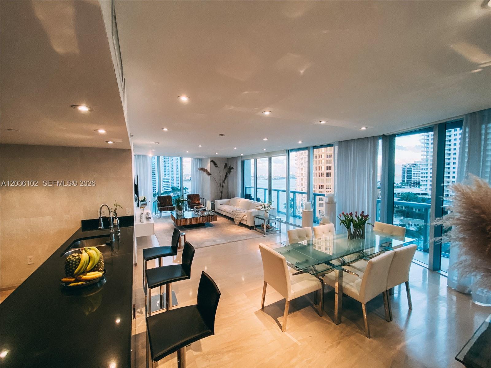 A modern open-concept living and dining area features a kitchen island, floor-to-ceiling windows, and balcony — 465 Brickell Ave # 1101, Miami FL 33131, MIAMI, FL
