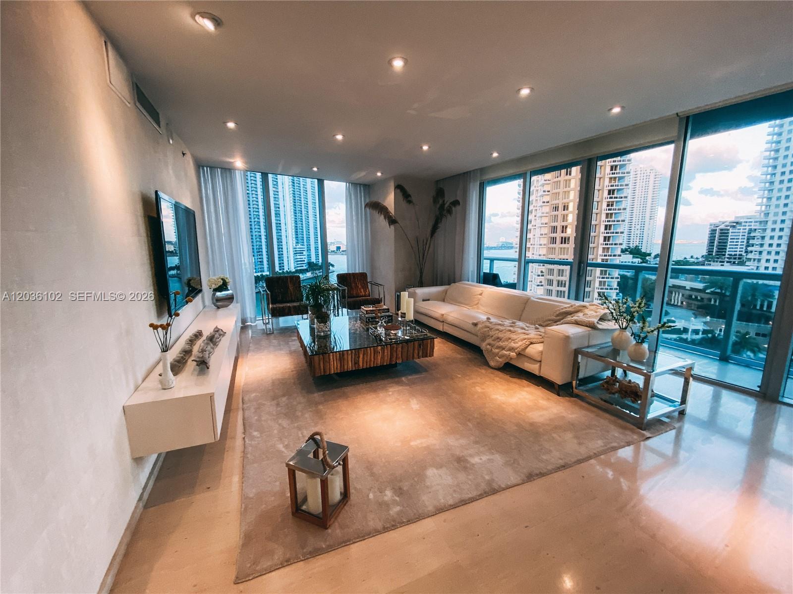 A modern living room features a white sofa, glass coffee table, and floor-to-ceiling windows — 465 Brickell Ave # 1101, Miami FL 33131, MIAMI, FL