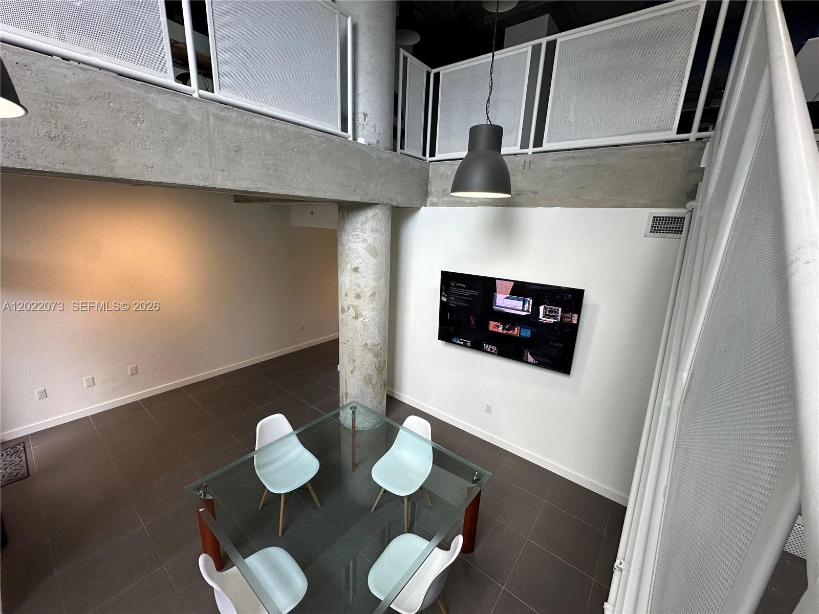 A dining area features a glass table, four chairs, a concrete pillar, and a wall-mounted television — 3250 NE 1st Ave # 311, Miami FL 33137, MIAMI, FL