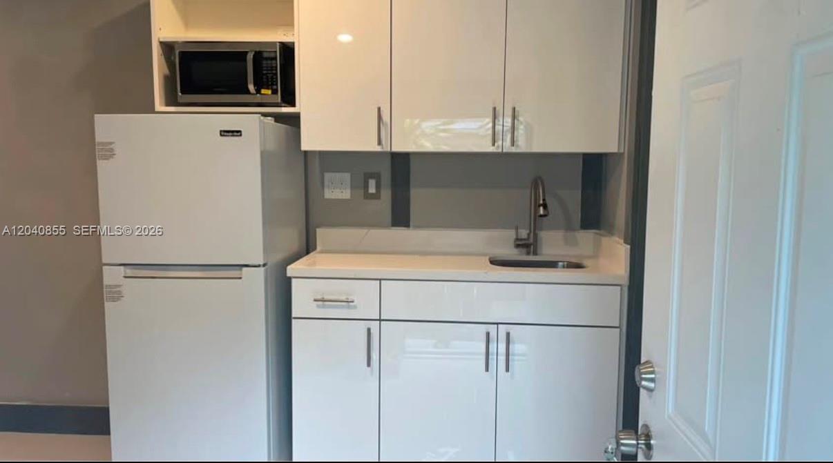 A small kitchenette features white cabinets, a stainless steel sink, and a white refrigerator — 420 NW 95th St # 420, Miami FL 33150, MIAMI, FL