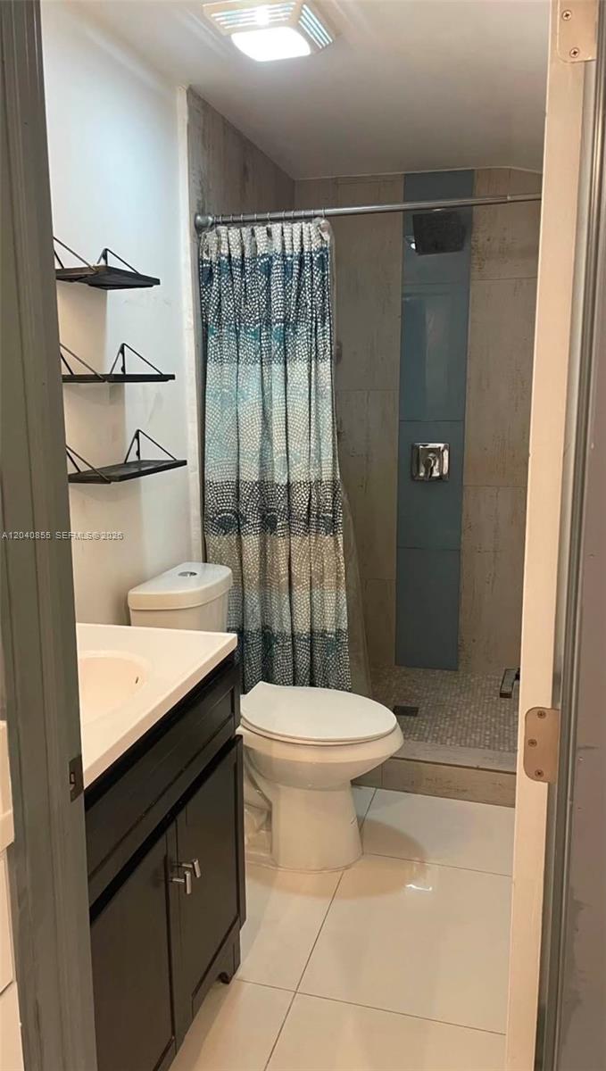 A bathroom features a vanity, a toilet, and a walk-in shower with a patterned curtain — 420 NW 95th St # 420, Miami FL 33150, MIAMI, FL