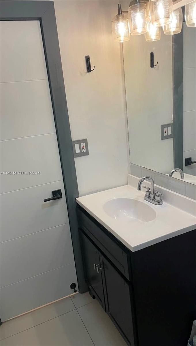 A bathroom features a dark vanity with a white sink, a mirror, and a door — 420 NW 95th St # 420, Miami FL 33150, MIAMI, FL