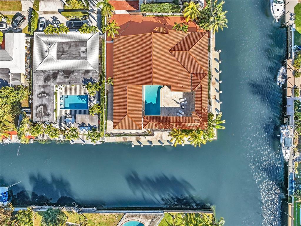 An aerial view shows a waterfront house with a tiled roof and a private pool — 12904 BANYAN ROAD, NORTH MIAMI, FL