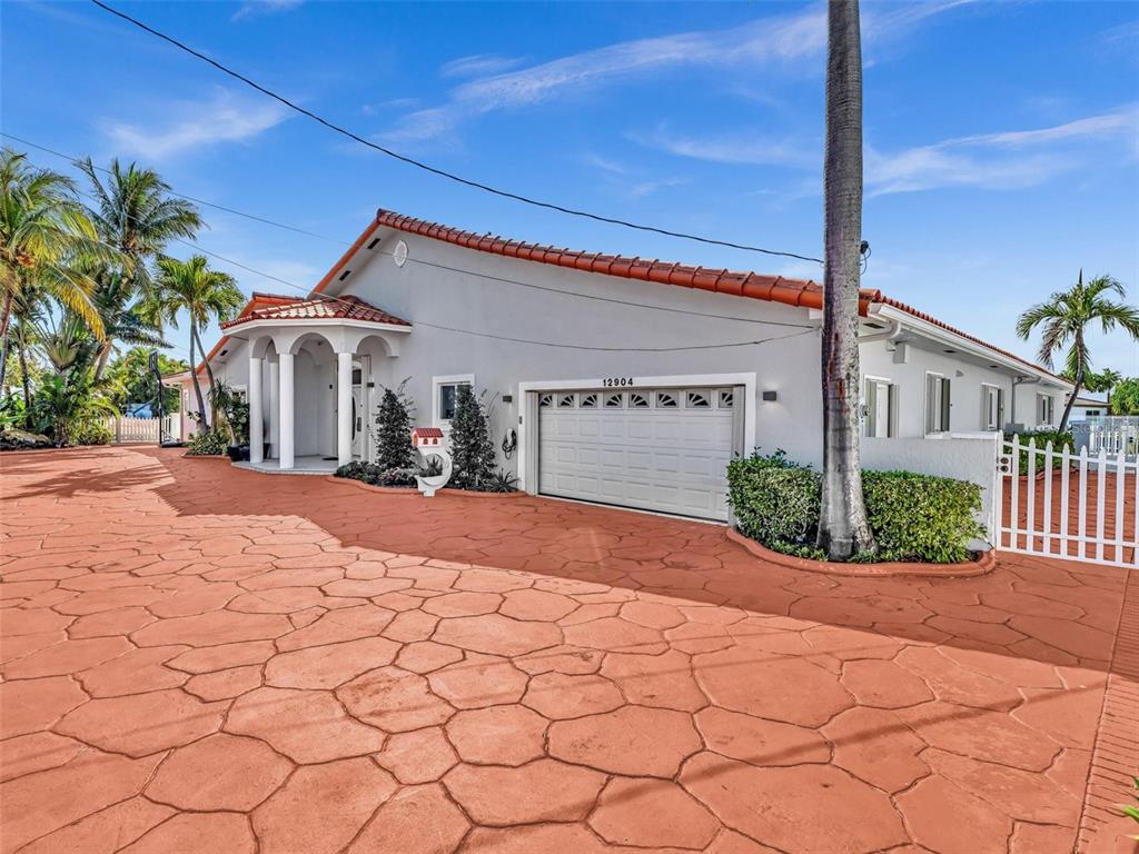 A single-story house with a white garage, arched entryway, and a stamped concrete driveway — 12904 BANYAN ROAD, NORTH MIAMI, FL