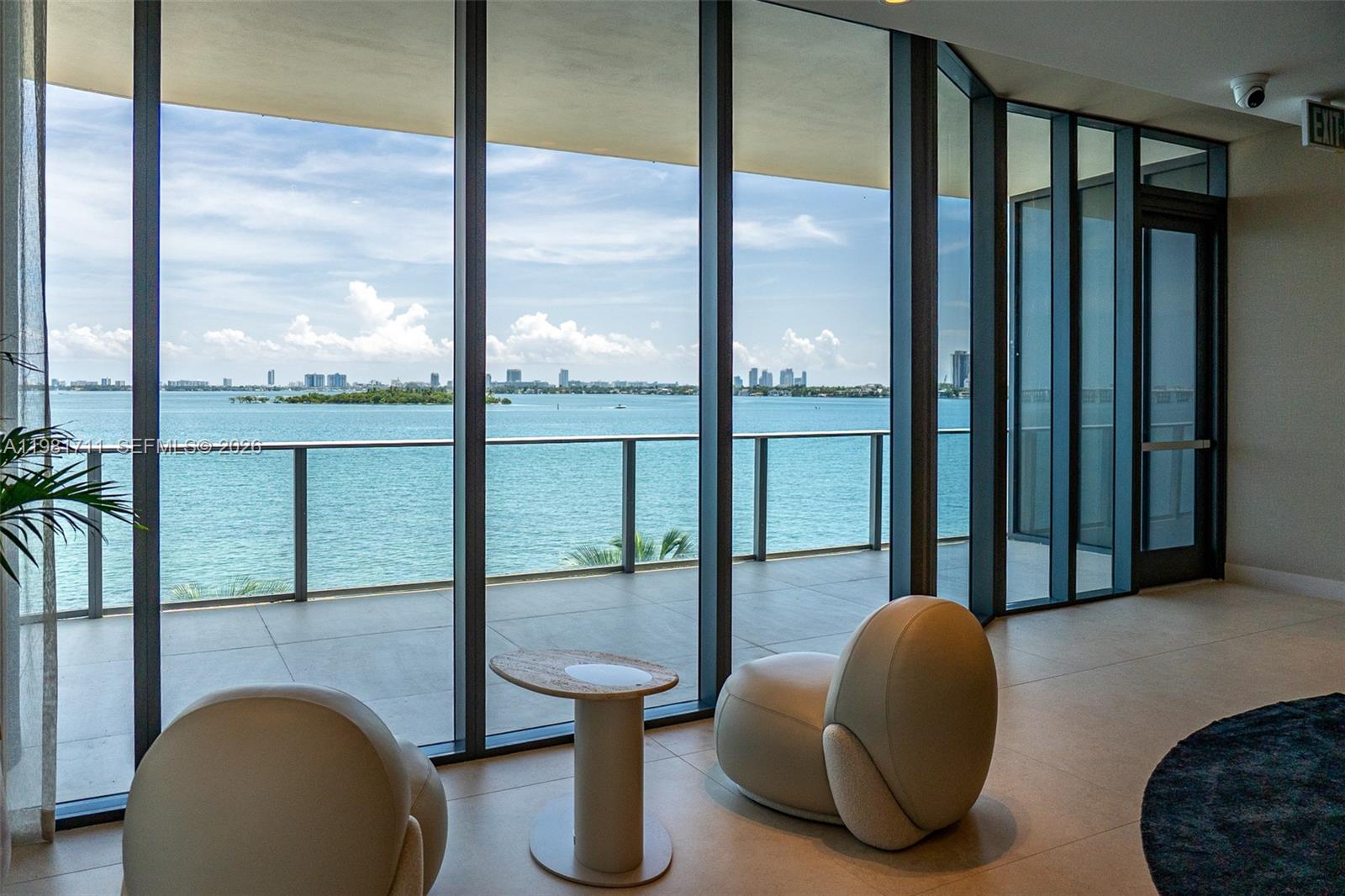 A modern room features floor-to-ceiling windows overlooking a balcony, the ocean, and a city skyline — 700 NE 24th st # 3603, Miami FL 33137, MIAMI, FL