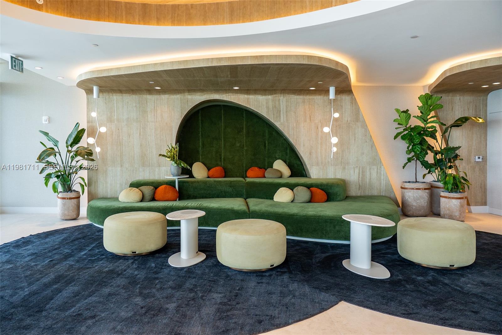 A modern lounge area features a large green velvet sofa, circular ottomans, and wood-paneled walls — 700 NE 24th st # 3603, Miami FL 33137, MIAMI, FL