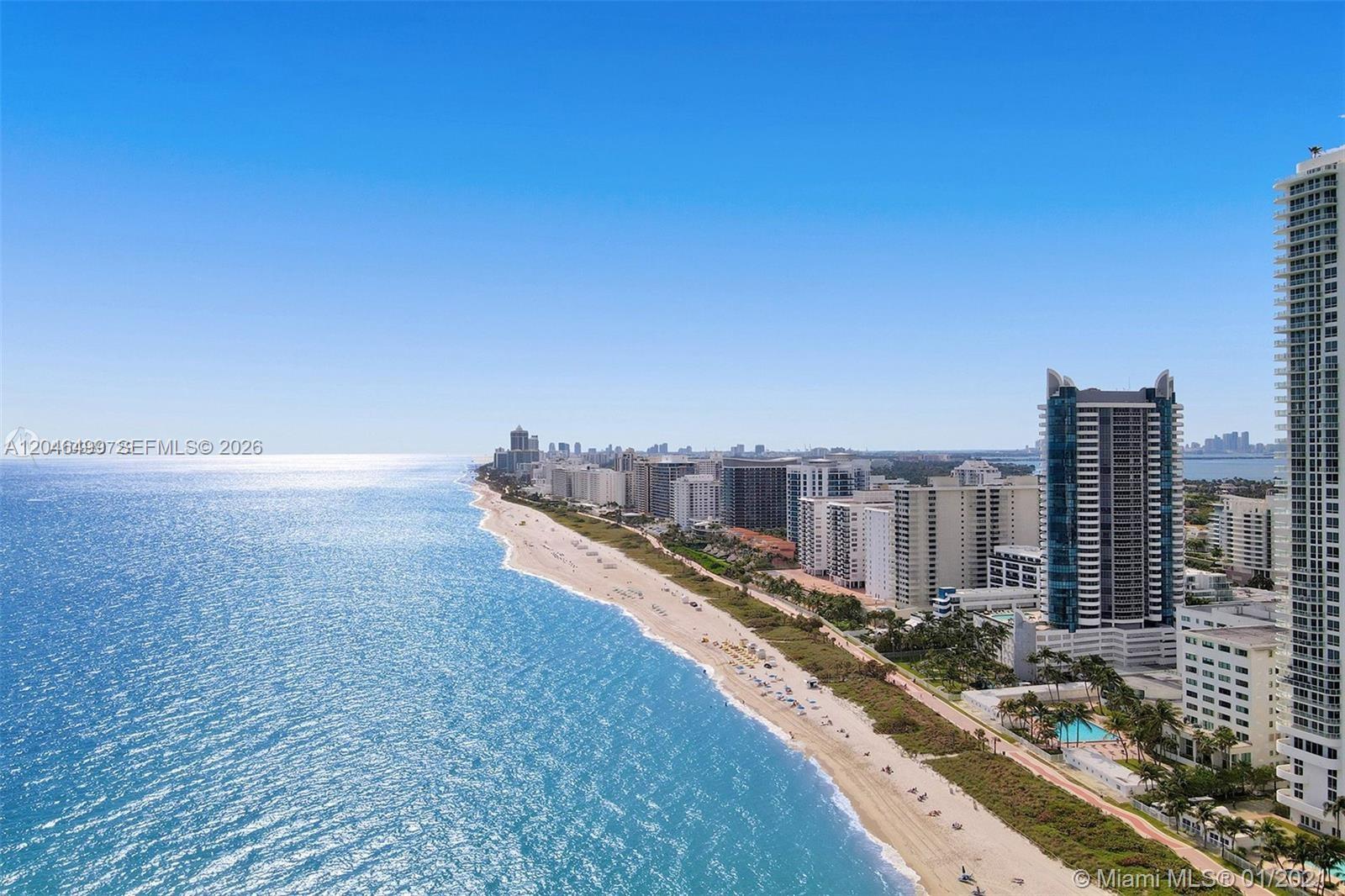 An aerial view of a sandy beach coastline lined with high-rise residential buildings — 6301 Collins Ave # 807, Miami Beach FL 33141, MIAMI BEACH, FL