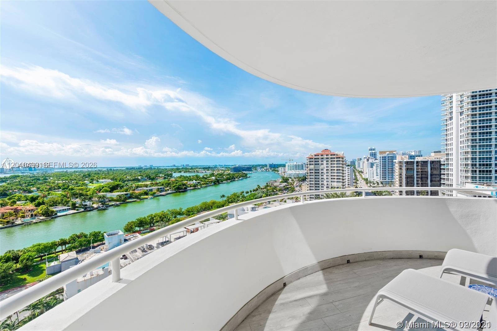 A curved balcony with white railings overlooks a waterway and city skyline — 6301 Collins Ave # 807, Miami Beach FL 33141, MIAMI BEACH, FL