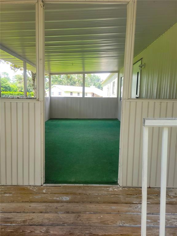 A covered porch with green outdoor carpeting and white metal walls overlooks a backyard — 17855 SE 15TH COURT, SUMMERFIELD, FL