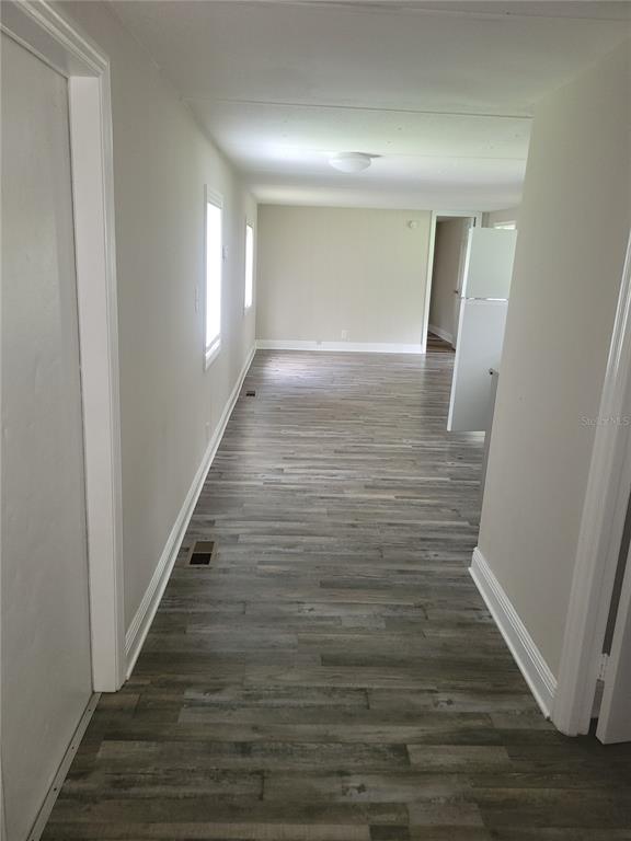 A hallway with wood-look flooring leads into an open living area with white walls — 17855 SE 15TH COURT, SUMMERFIELD, FL