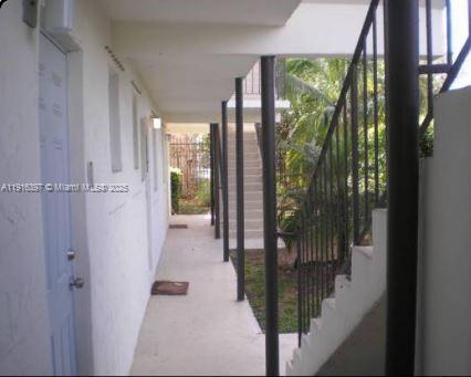 An outdoor walkway with a light blue door, metal railings, and stairs leading to another level — 3680 Oak Ave # 6, Miami FL 33133, MIAMI, FL