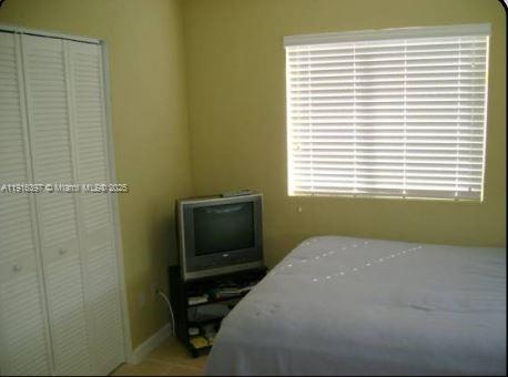 A bedroom features a white louvered closet, a small television on a stand, and a window — 3680 Oak Ave # 6, Miami FL 33133, MIAMI, FL