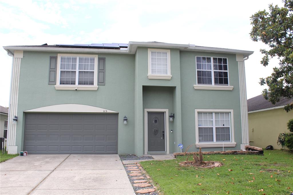 A two-story light green house with a two-car garage and a paved driveway — 115 WILLOWBAY RIDGE STREET, SANFORD, FL