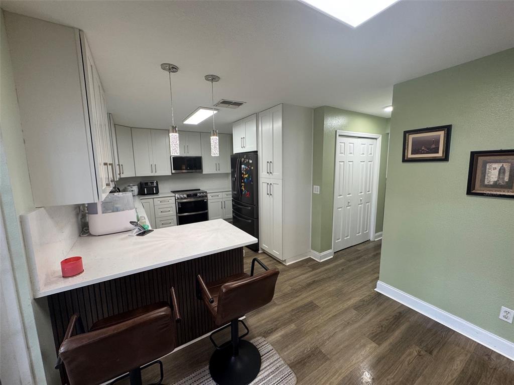 A kitchen features white cabinets, a breakfast bar with stools, and light green walls — 115 WILLOWBAY RIDGE STREET, SANFORD, FL