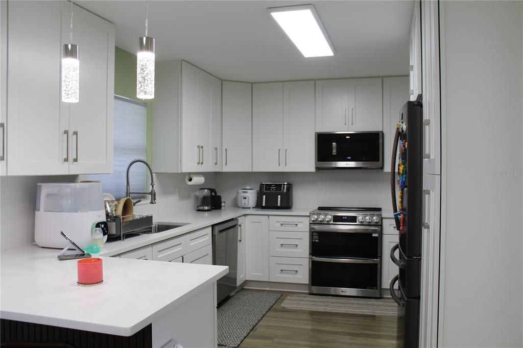 A modern kitchen features white cabinetry, stainless steel appliances, and a white countertop — 115 WILLOWBAY RIDGE STREET, SANFORD, FL