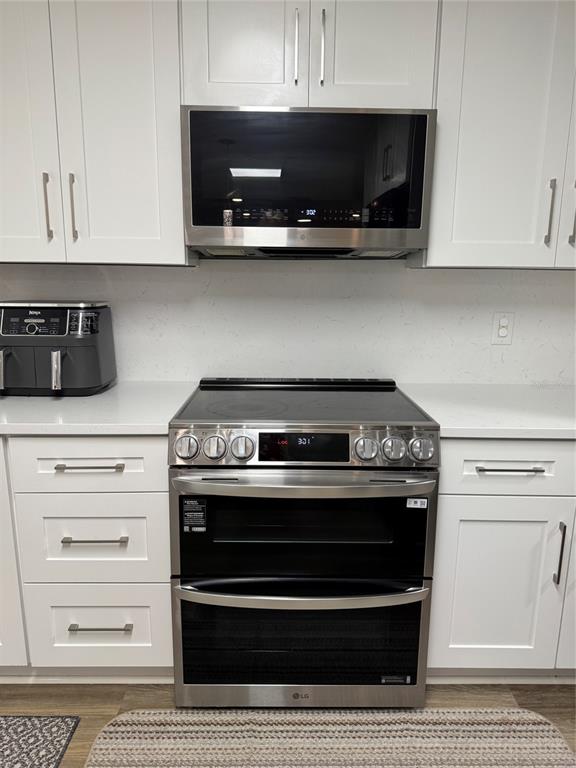 A kitchen features white cabinets, stainless steel appliances, and a quartz countertop — 115 WILLOWBAY RIDGE STREET, SANFORD, FL
