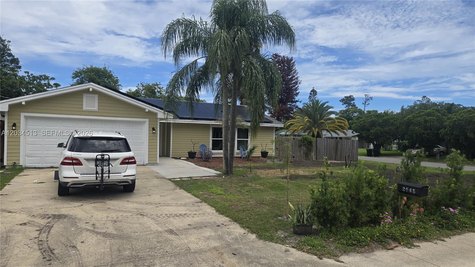 A single-story house with yellow siding, a white garage door, and a palm tree — 2845 OAK LEA DR, Daytona FL 32119, DAYTONA, FL