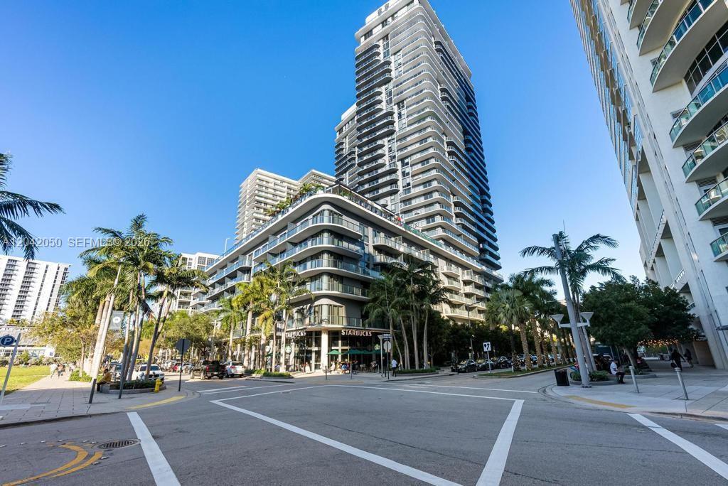 A modern high-rise building with a Starbucks on the ground floor stands near a street — 121 NE 34th St # 2205, Miami FL 33137, MIAMI, FL